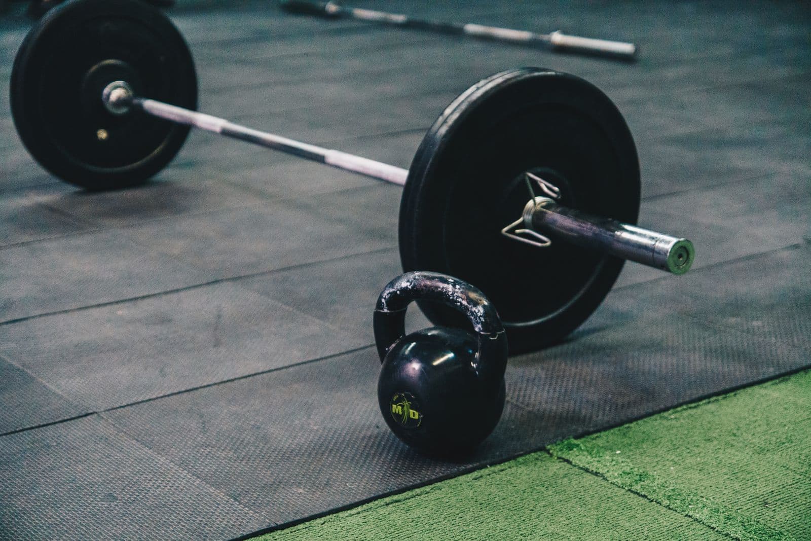 Langhantel und Kettlebell auf dem Boden des Freihantelbereichs